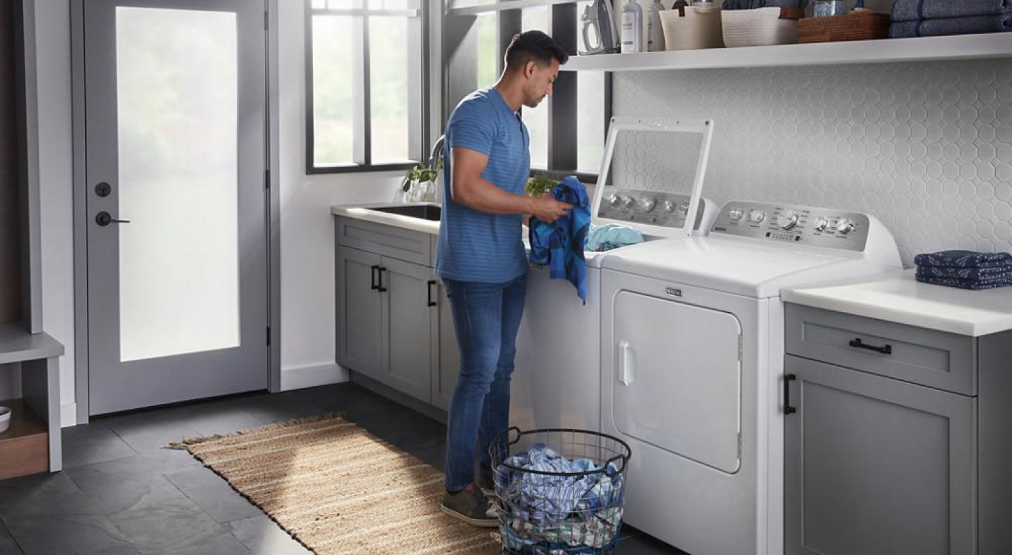 Person placing clothes into a top load washing machine Person placing clothes into a top load washing machine