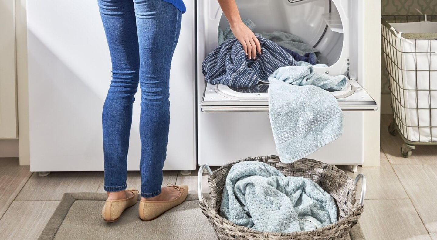 A woman unloading dry laundry into a basket A woman unloading dry laundry into a basket