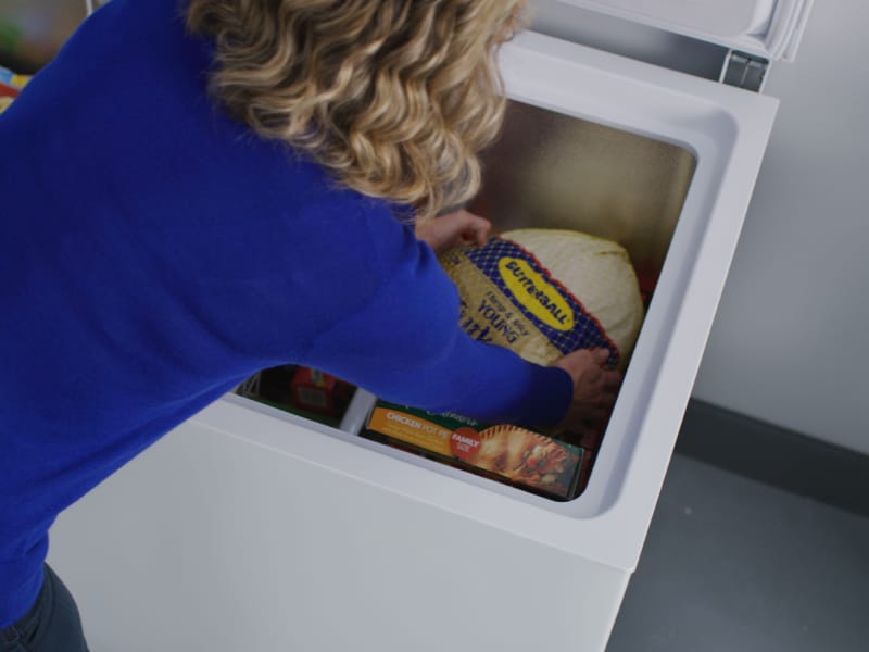 Person placing turkey in a freezer Person placing turkey in a freezer