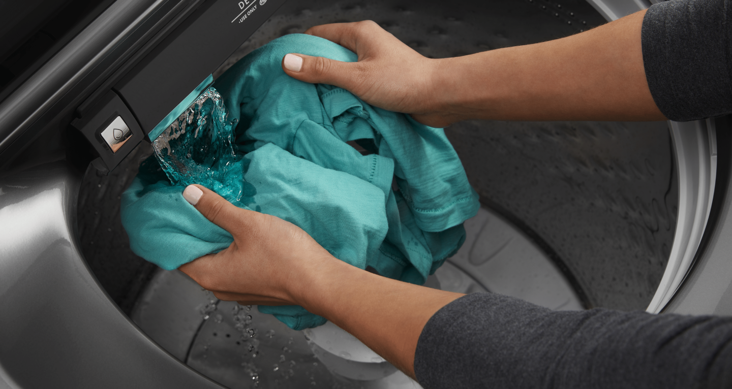 Person rinsing garment under water flow in Maytag® washing machine Person rinsing garment under water flow in Maytag® washing machine
