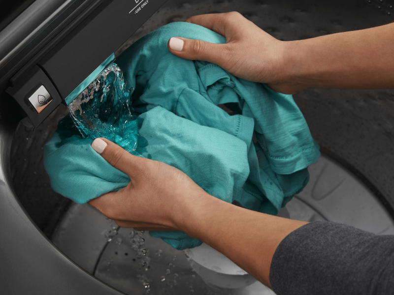 Person rinsing garment under water flow in Maytag® washing machine Person rinsing garment under water flow in Maytag® washing machine