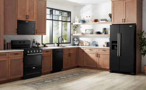 A kitchen with wood cabinets with black fixtures and black appliances