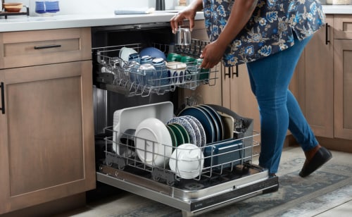 Person loading dishes into a Maytag® dishwasher