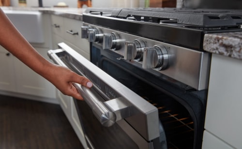 Person cracking open the door of a gas oven