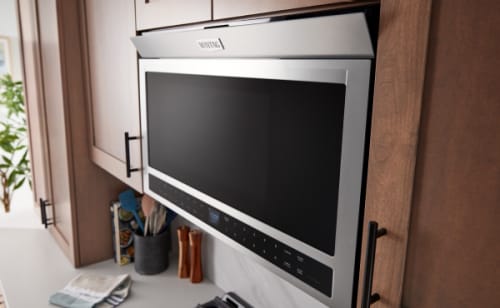 Flush Maytag® microwave against cabinets with its vent open