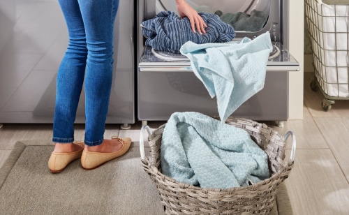 A close up of a person removing laundry from a Maytag® dryer