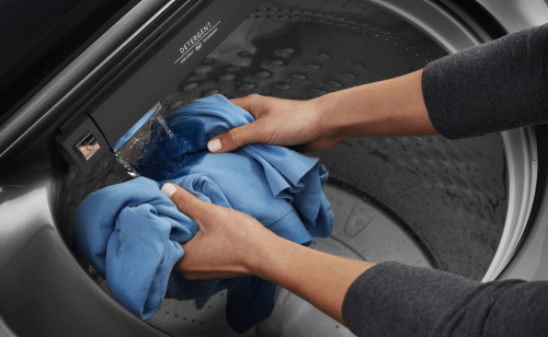 Person rinsing blue clothes in washing machine