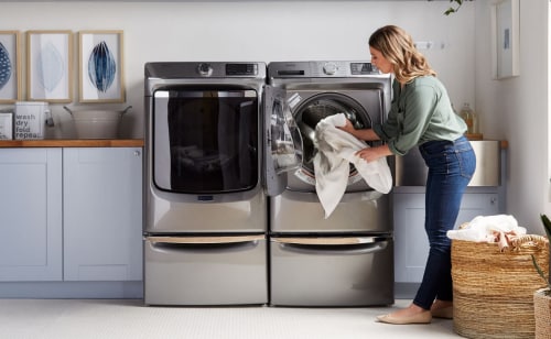 Person putting sheets in a Maytag® dryer